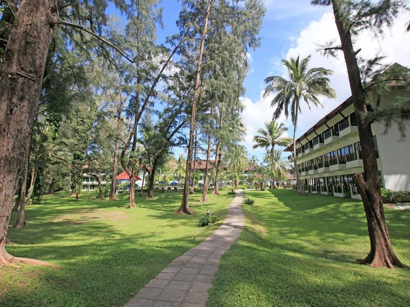 Green hotel grounds with pathway and trees under a blue sky.