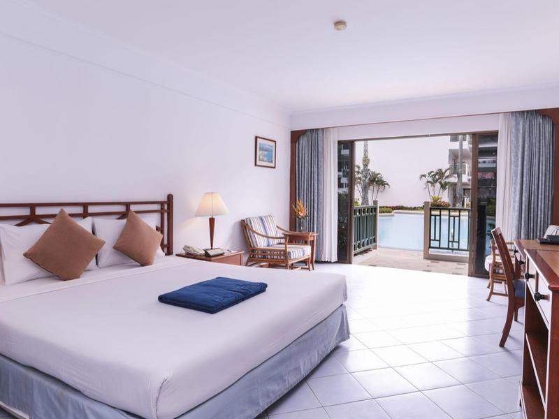 Bright hotel room with double bed and balcony overlooking the sea.