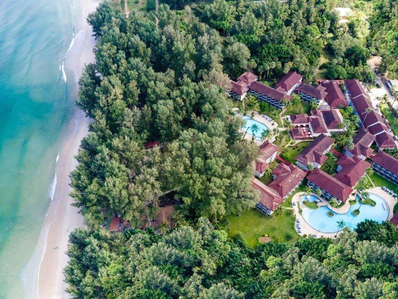 Luxury resort with pool in tropical forest by a beach with clear water.