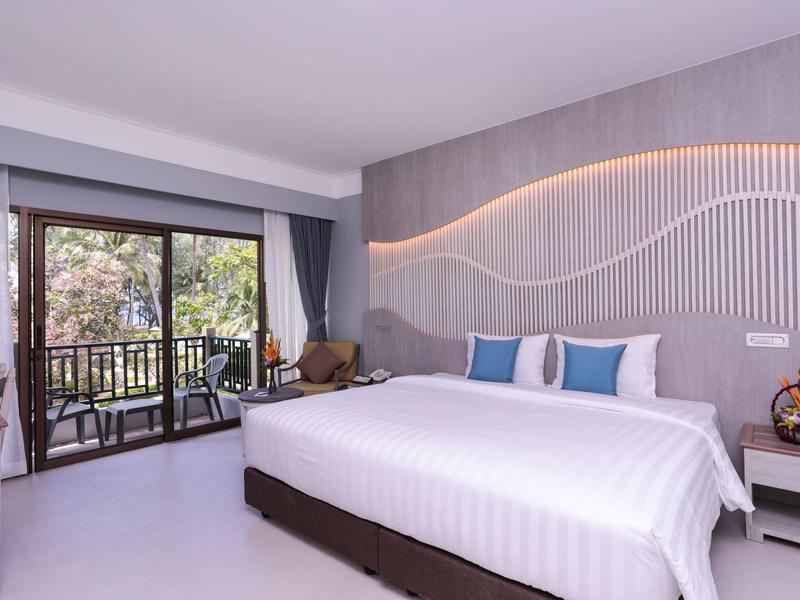 Modern hotel room with large bed, balcony, and stylish wall lighting.