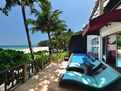 Terrace with loungers and private pool, sea view and palm trees by the beach.
