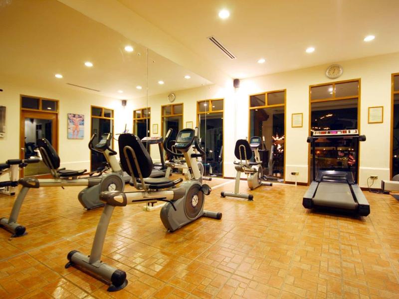 Fitness room with various exercise machines and large windows in a hotel.