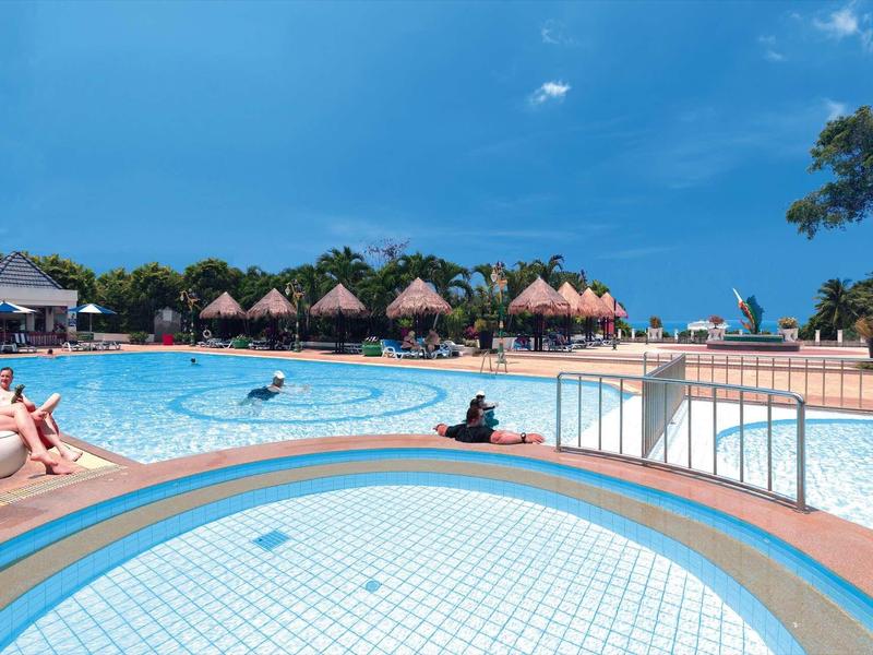 Großer Außenpool mit blauem Wasser, umgeben von Relaxliegen und lauschigen Palmenhütten.