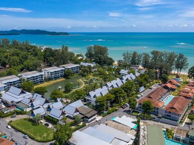 Vogelperspektive eines Strandresorts mit Pools, Gärten und Blick aufs Meer unter blauem Himmel.
