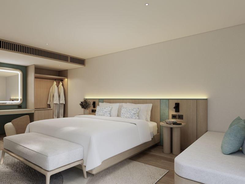 Modernes Schlafzimmer mit großem Bett, Sitzbank, Kleiderschrank und Sofa in neutralen Tönen.