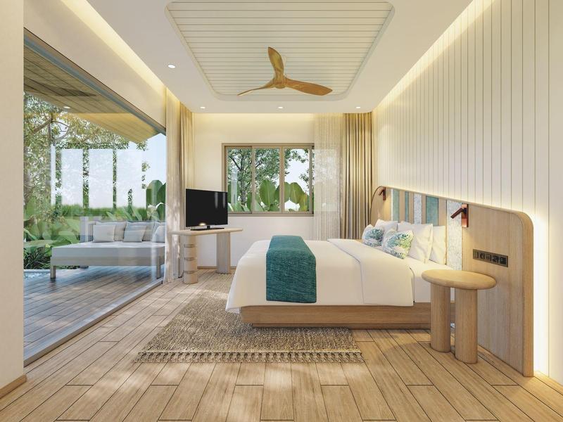 Helles Hotelzimmer mit großem Bett, Holzfußboden und Blick auf eine Terrasse mit Pflanzen.