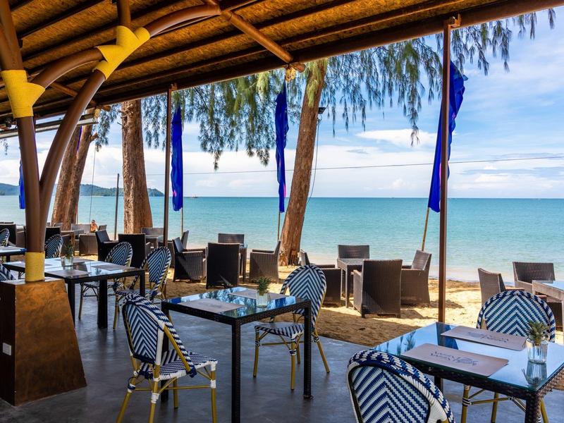 Offenes Restaurant mit Tischen und Stühlen mit Blick auf den Strand und das Meer