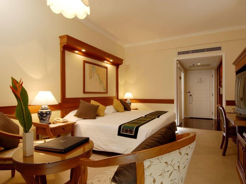 Gemütliches Hotelzimmer mit Doppelbett, Nachttischen, Tisch, Stühlen und warmem Licht.