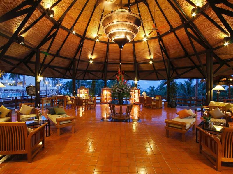 Großer, offener Pavillon mit Holzstuhlgruppen und warmem Licht bei Dämmerung.