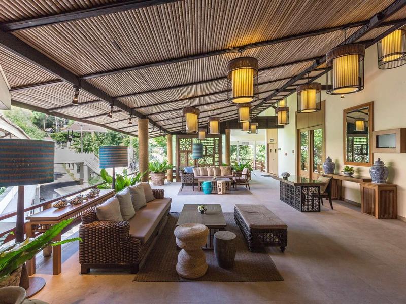 Moderne, offene Terrasse mit Holzmöbeln, Lampen, Grünpflanzen und Blick in einen Garten.