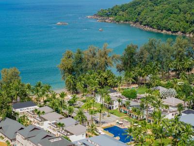 Blick auf eine tropische Hotelanlage mit Pool, Palmen und dem Ozean im Hintergrund.