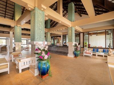 Helle Hotellobby mit weißen Möbeln, großen Säulen und Blumenarrangements in dekorativen Vasen.