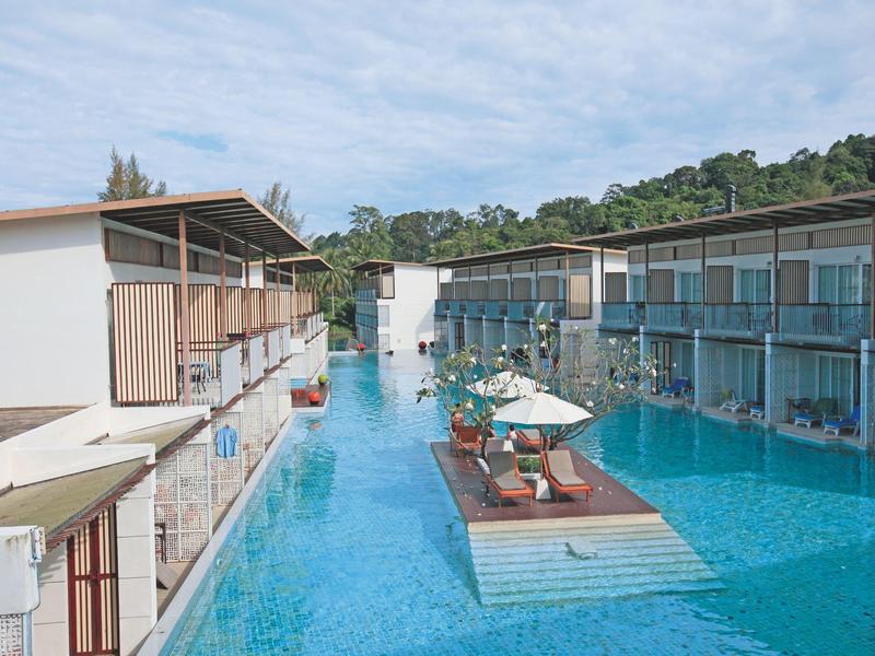 Moderner Hotelpool mit Sonnenschirmen und Liegestühlen zwischen zwei Gebäuden.