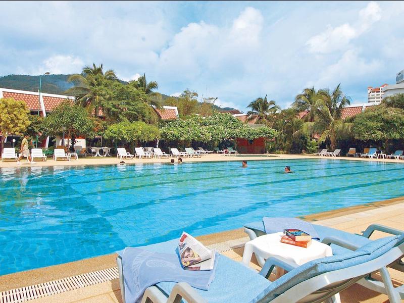 Gran piscina al aire libre con tumbonas en complejo hotelero tropical bajo el sol.