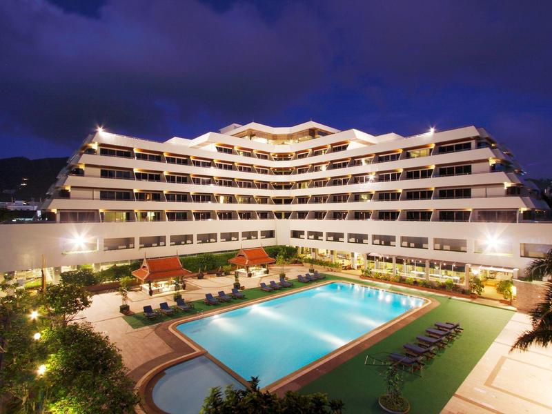 Hotel moderno con gran piscina y terraza iluminada por la noche.