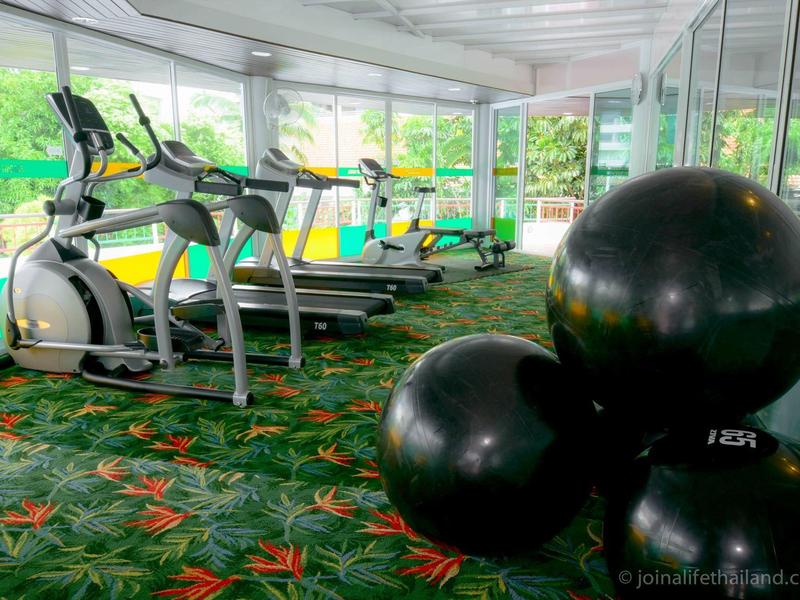 Equipos de fitness modernos y pelotas de gimnasia en una sala de ejercicios iluminada con paredes de vidrio.