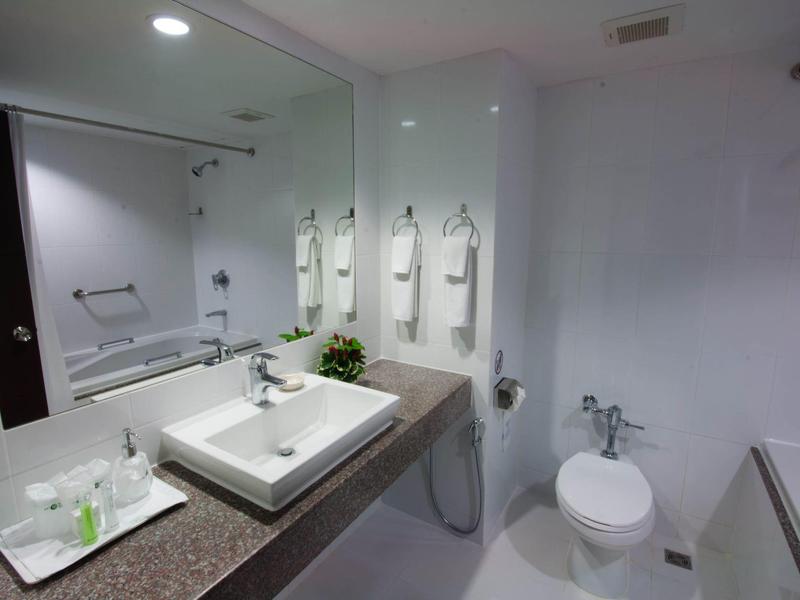 Baño moderno de hotel con lavabo, inodoro, bañera y espejos grandes.