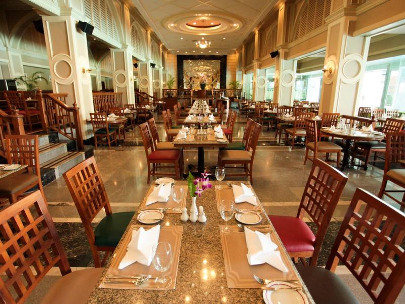 Restaurante elegante con mesas largas, sillas de madera y grandes ventanales que aportan mucha luz natural.