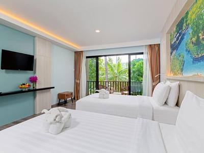 Chambre d'hôtel moderne avec deux lits blancs, grande fenêtre et balcon avec vue sur des palmiers.