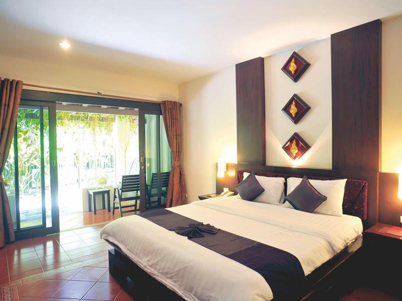 Chambre d'hôtel moderne avec grand lit, mobilier sombre et balcon avec vue sur jardin.