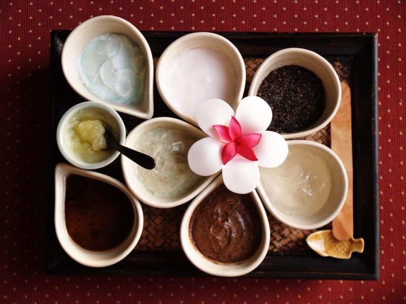 Différentes crèmes et poudres dans des bols sur un plateau, décorées d'une fleur blanche