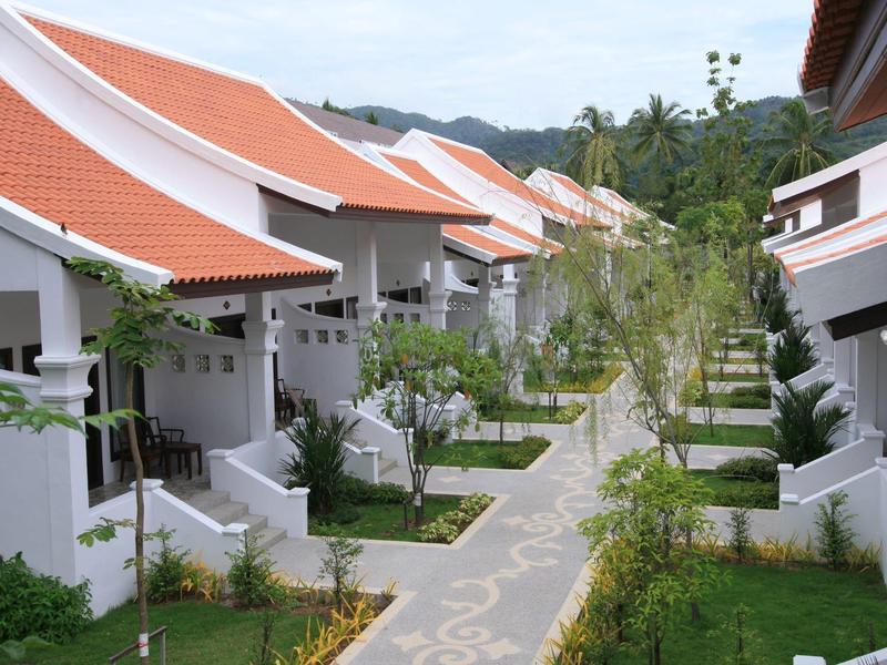 Alignement de maisons de vacances modernes aux toits rouges le long d'un chemin pavé vert.