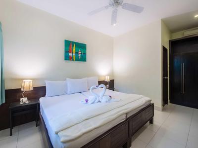 Modernes Schlafzimmer mit großem Bett, weißen Bettwäsche, Nachttischen und Deckenventilator.