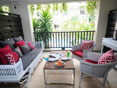 Heller Balkon mit Sitzgruppe, grauen Kissen, roten Akzenten und einem kleinen Tisch mit Snacks.