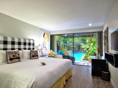 Modernes Hotelzimmer mit großem Bett, TV, Schreibtisch und Blick auf einen Pool im Grünen.