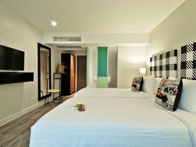 Hell eingerichtetes Hotelzimmer mit zwei Betten, Flachbildfernseher und modernem Ambiente.