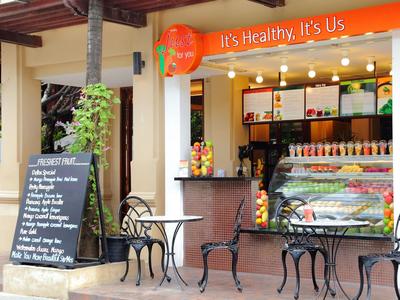 Zewnętrzny obszar małego sklepu z sokami z miejscami do siedzenia i tablicą menu.