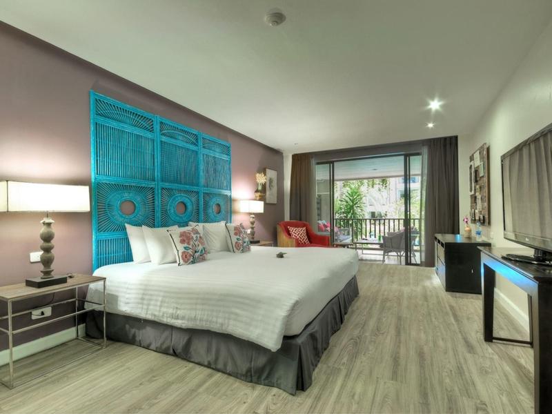 Modernes Hotelzimmer mit großem Bett, Holzboden, Balkon und heller Beleuchtung.