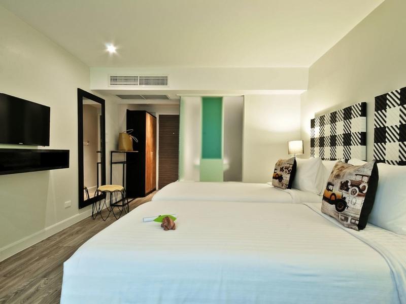 Hell eingerichtetes Hotelzimmer mit zwei Betten, Flachbildfernseher und modernem Ambiente.