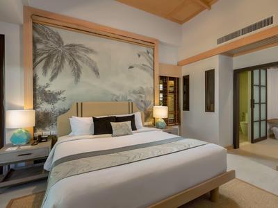 Gemütliches Hotelzimmer mit großem Bett, Palmwandbild und indirekter Beleuchtung.