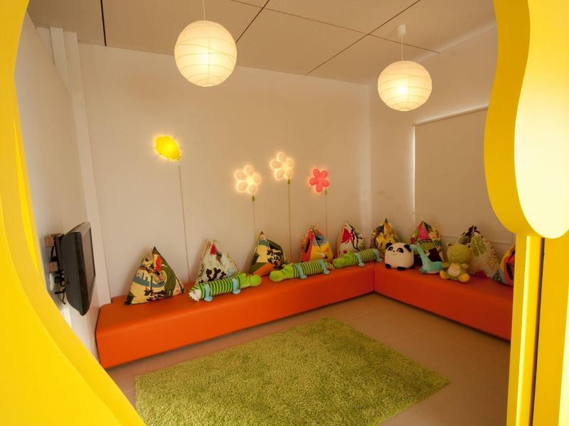 Gemütliche Sitzecke mit bunten Kissen und Kuscheltieren in einem kinderfreundlichen Raum.