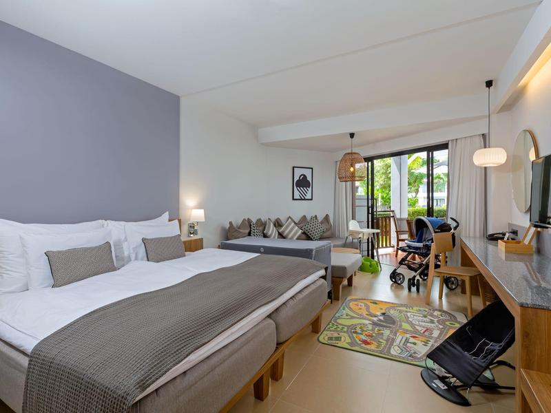 Modern eingerichtetes Schlafzimmer mit Doppelbett, Sitzbereich, Schreibtisch und Zugang zum Balkon.