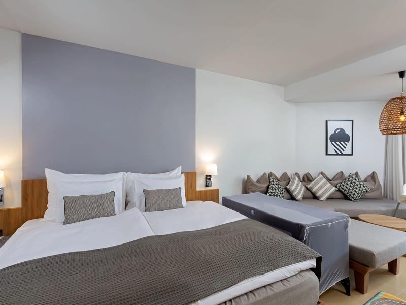 Modernes Hotelzimmer mit Doppelbett, Sitzecke, Lampen und minimalistischer Dekoration.