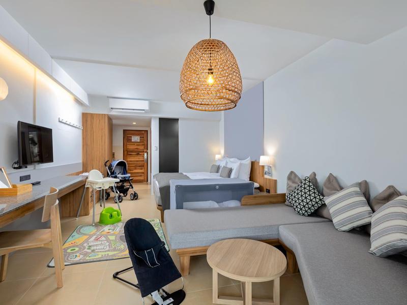 Modern eingerichtetes Hotelzimmer mit Sofa, Esstisch, Stühlen und Arbeitsbereich.