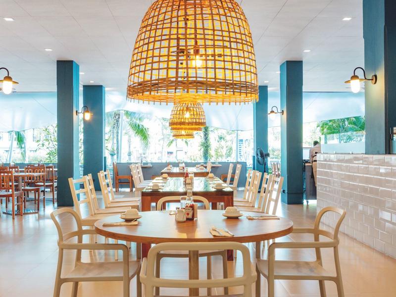 Modernes Restaurant mit hellen Holzmöbeln und großen Korblampen über den Tischen.