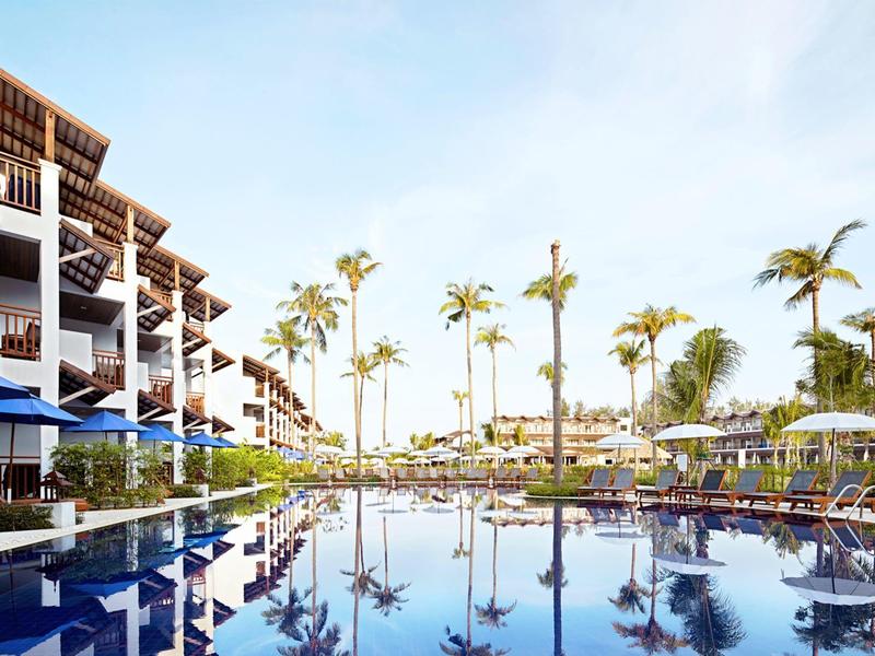 Moderner Hotelpool mit Palmen und Liegestühlen unter klarem Himmel