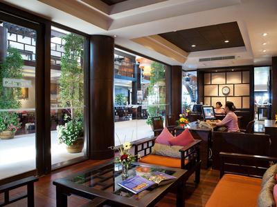 Gemütliches Café mit großen Fenstern, Holzmöbeln und einer Person am Tisch.