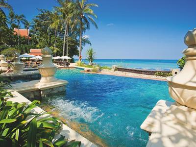 Tropischer Pool mit blauer Wasserfläche, Palmen, Pflanzen und blauem Himmel am Meer.