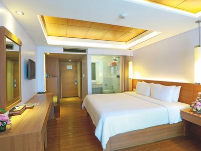 Helles Hotelzimmer mit Doppelbett, Holzmöbeln und moderner Beleuchtung.