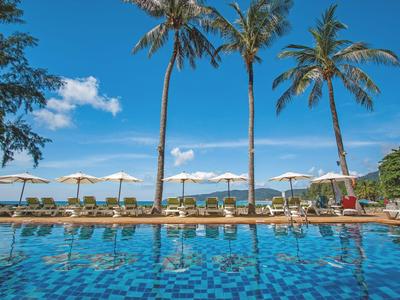 Grande piscina con piastrelle blu e lettini sotto palme in una giornata di sole