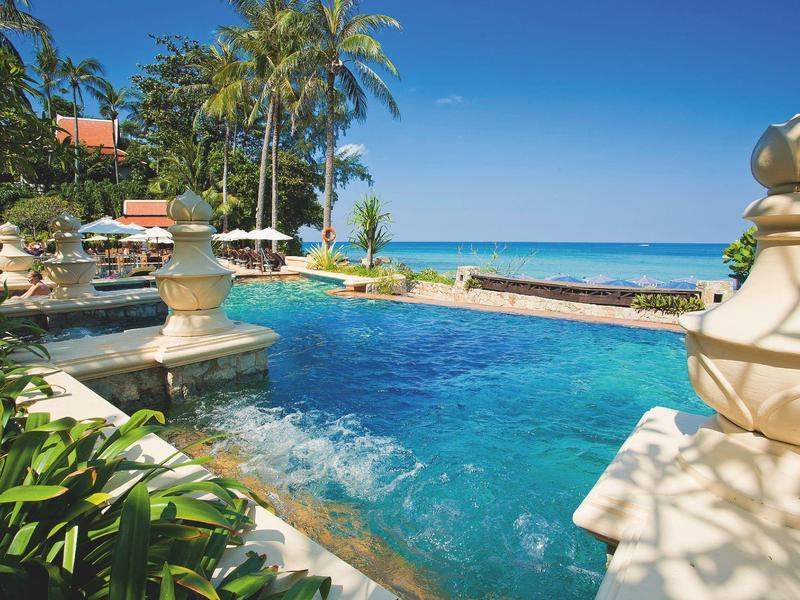 Tropischer Pool mit blauer Wasserfläche, Palmen, Pflanzen und blauem Himmel am Meer.