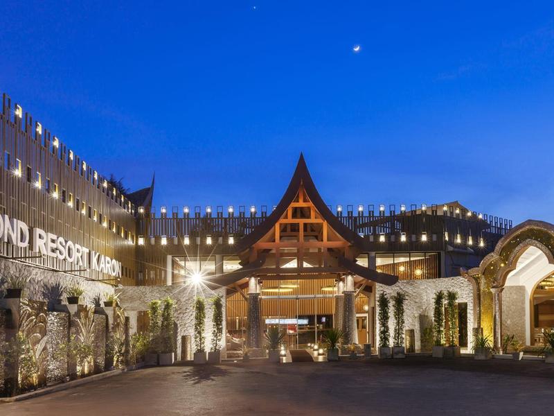 Großes Resort mit beleuchteten Gebäuden, Holzdach und klarem blauem Abendhimmel.