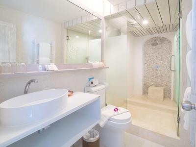 Helles Badezimmer mit rundem Waschbecken, Toilette und begehbarer Dusche mit Steinmauer.