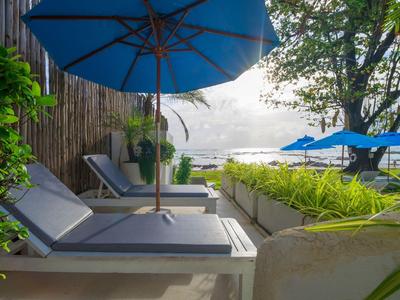 Gemütliche Liegen mit blauen Sonnenschirmen am Strand mit Meerblick.