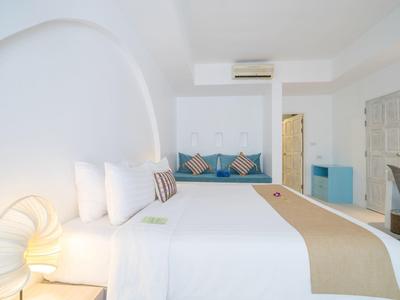 Helles, modernes Schlafzimmer mit großem Bett, blauem Sitzbereich und minimalistischem Lampendesign.