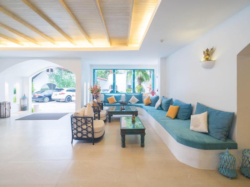 Helle Hotellobby mit langem blauen Sofa, bunten Kissen und modernen Sesseln.